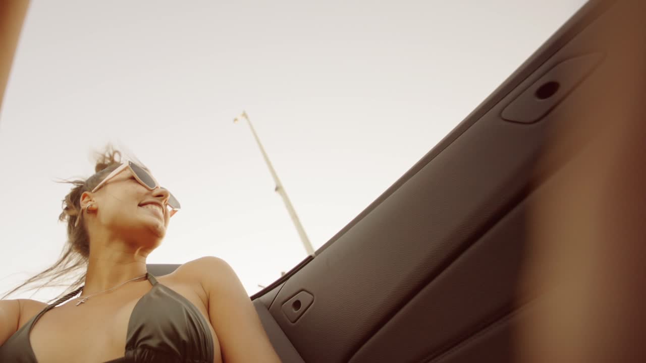 Woman in bikini enjoying a convertible ride