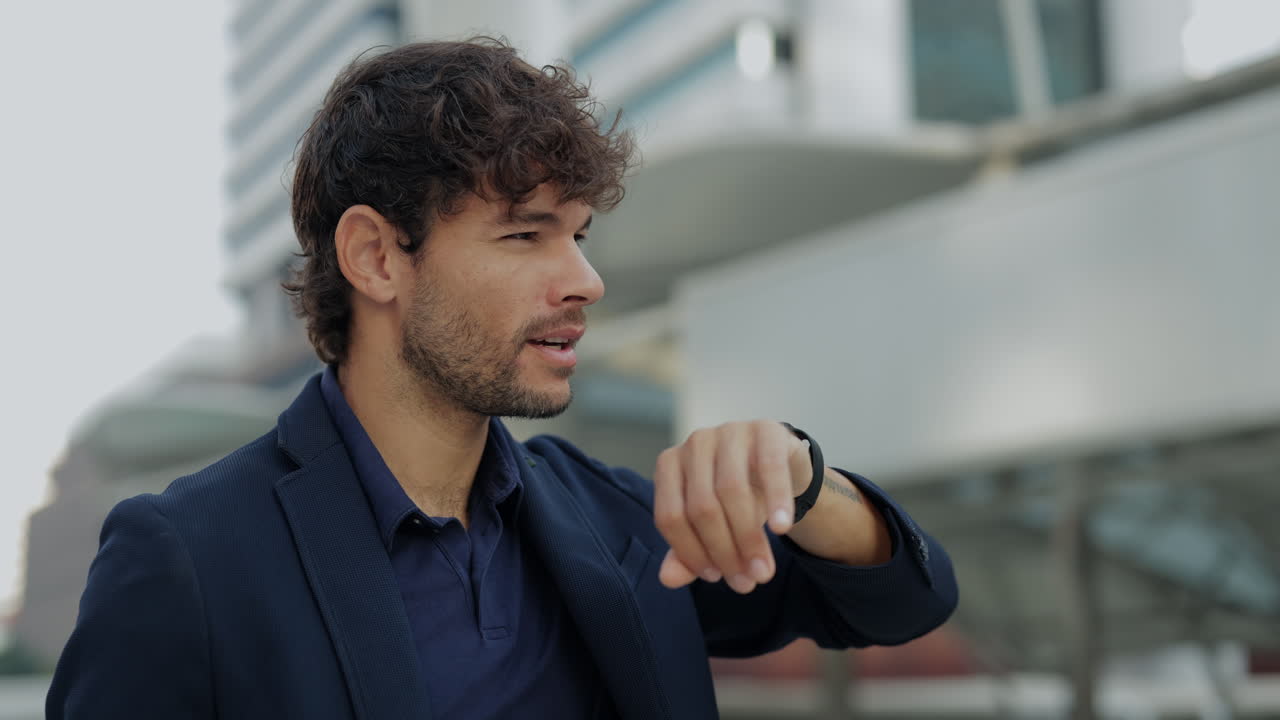 Giovane uomo d'affari che controlla l'ora sul suo orologio con impazienza
