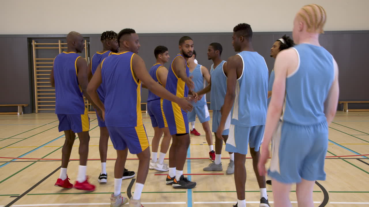 Basketball team huddling in gym, preparing for game with coach guidance