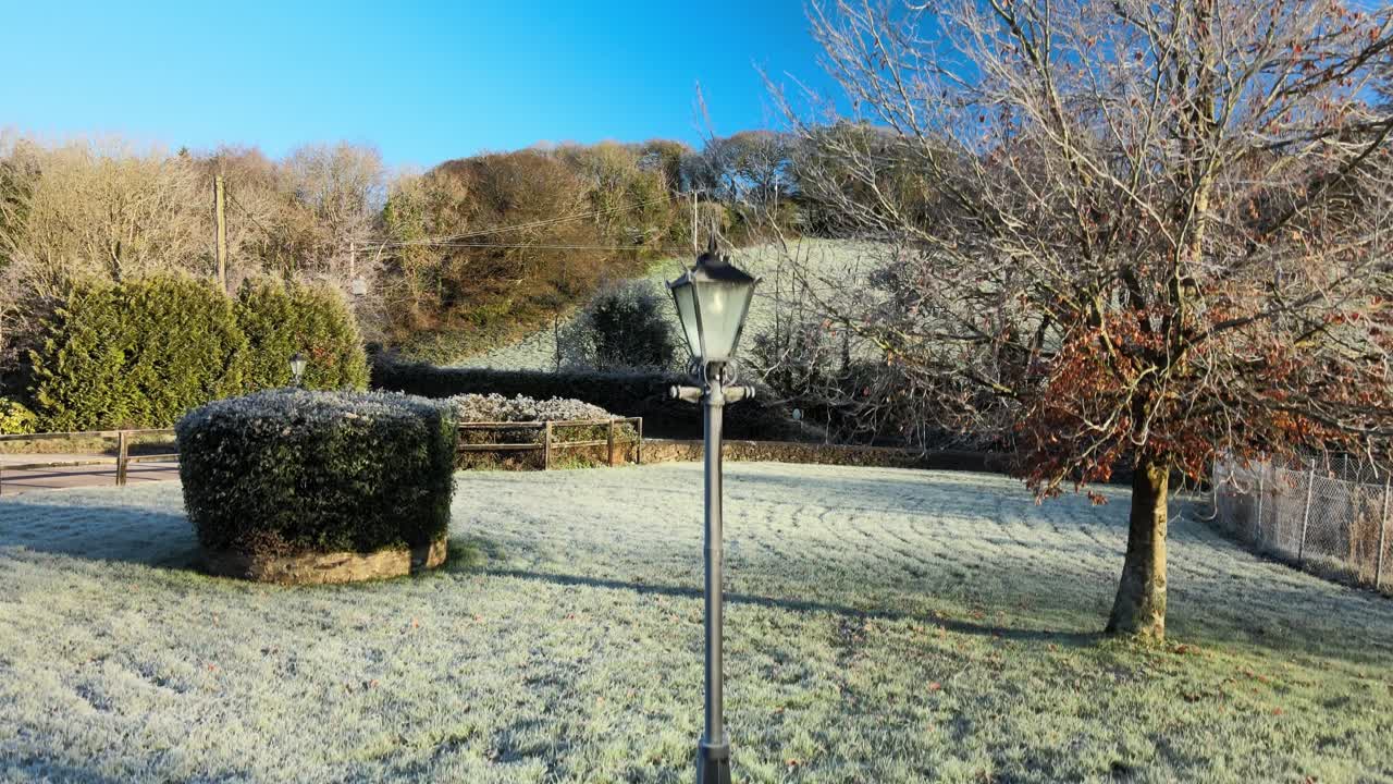 얼어붙은 가로등 위로 얼어붙은 땅에서 이륙하고 배경에 언덕이 있는 나무