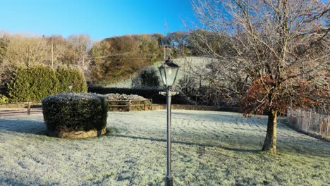 Liftoff-from-frozen-ground-over-frozen-street-lamp-and-a-tree-with-a-hill-in-the-background