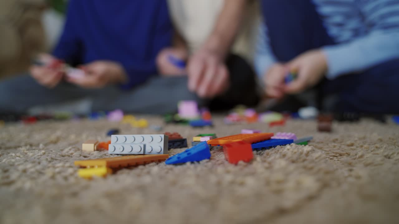Two boys build a building out of plastic blocks. ?hild playing with a toy constructor