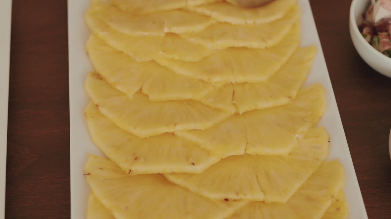 fresh pineapple slices arranged in overlapping layers on a white rectangular platter