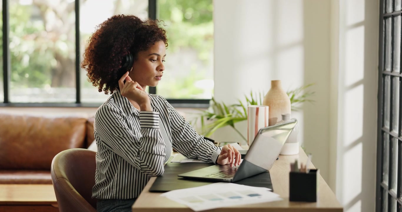Young Woman Working on Laptop and Wearing Headset in Home Office