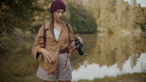 woman removing binoculars from her neck in forest