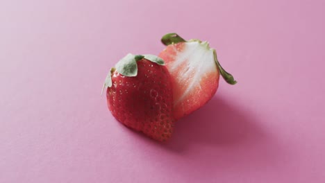 video of halved strawberry with copy space over pink background