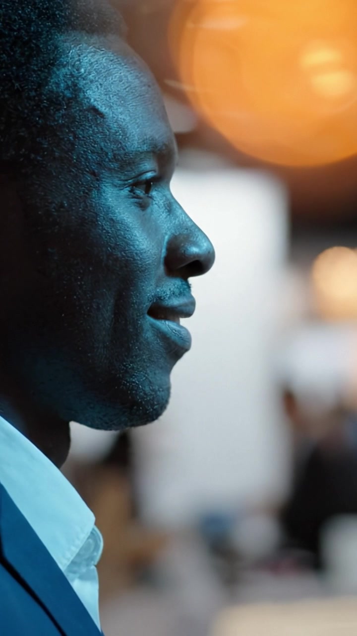A Side Profile Portrait of a Thoughtful Man in Professional Attire Surrounded by a Blurred, Busy Environment, Reflecting Concentration and Engagement