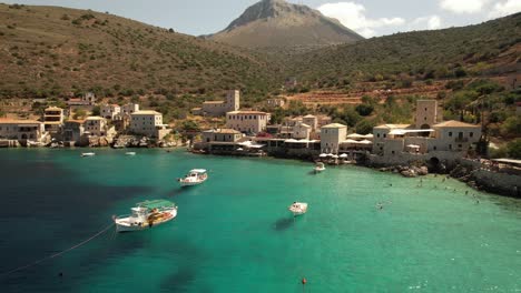 slow-drone-flight-above-the-beautiful-turquoise-water-with-small-fish-boats-and-stone-houses-somewhere-in-Greece