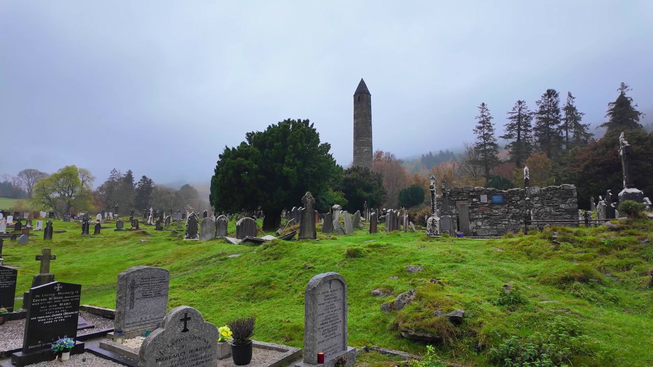 Luoghi iconici dell'Irlanda: inverno a Glendalough, torre rotonda e antico cimitero in una nebbiosa mattina d'inverno.