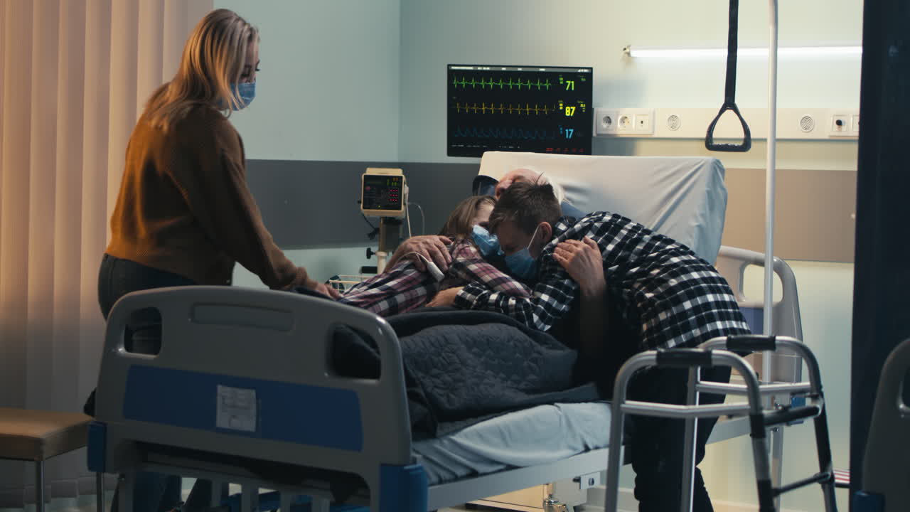 Family members visit and comfort an elderly patient in a hospital room