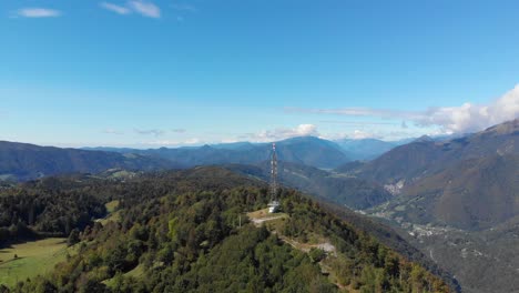 communications antenna on summit of vast mountain peak valley lush green hillside aerial orbit right