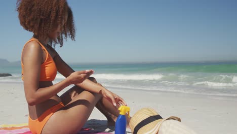 Afroamerikanische-Frau,-Die-Am-Strand-Sonnenschutzmittel-Aufträgt