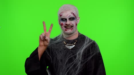 Halloween-zombie-man-bloody-make-up-showing-victory-sign,-hoping-for-success-and-win-peace-gesture