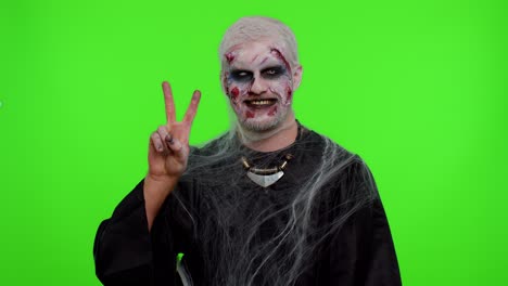 halloween hombre zombi maquillaje sangriento mostrando el signo de la victoria, con la esperanza de éxito y ganar el gesto de paz