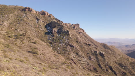 Aerial-reveal-over-cactus,-agave,-juniper-plants-in-desert-snow-into-desert-valley