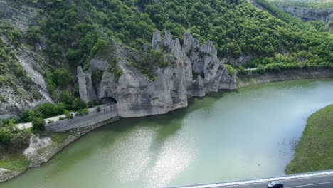 road passes under iconic rock formations next to tsonevo reservoir, aerial