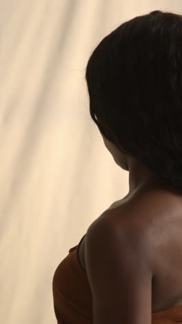 studio beauty shot of young woman with long hair against neutral background viewed in profile