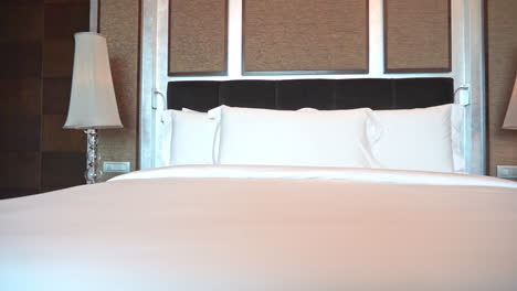 kingsize bed in hotel bedroom, white sheets, pillows and lamps, panorama