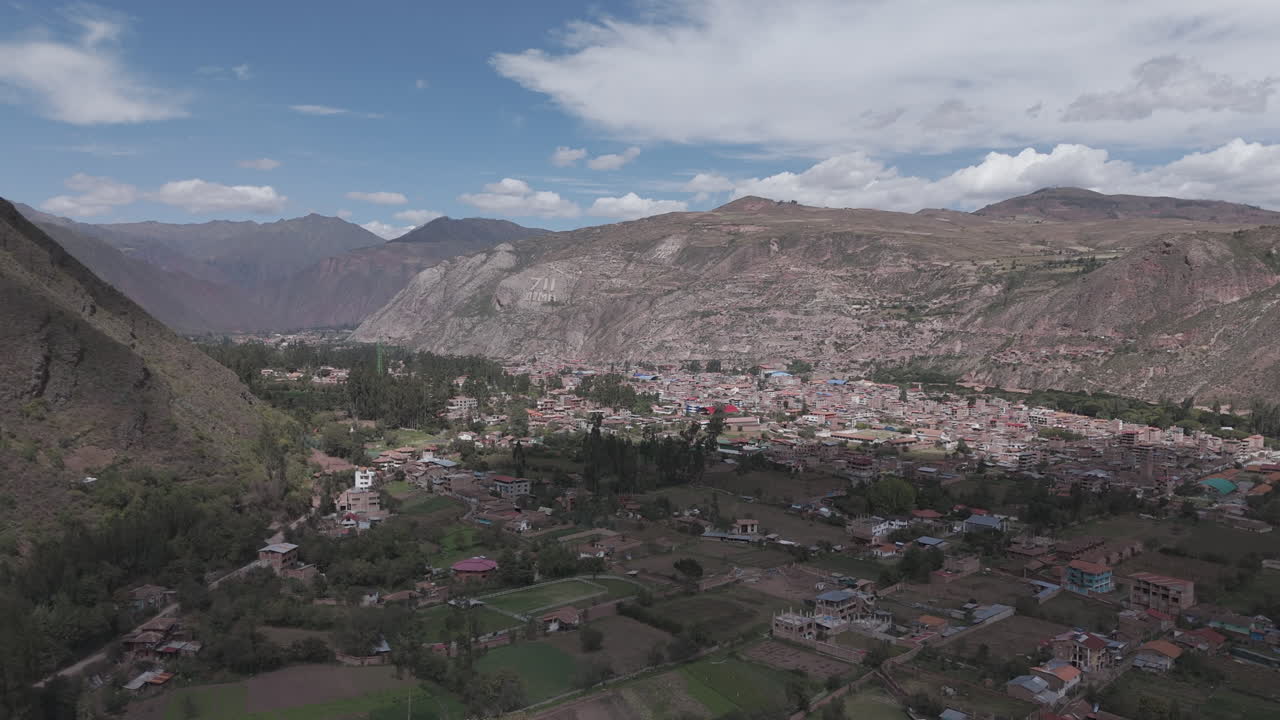 Drone shot above Urubamba Peru near Cuzco between the mountain on a bright day with clouds LOG