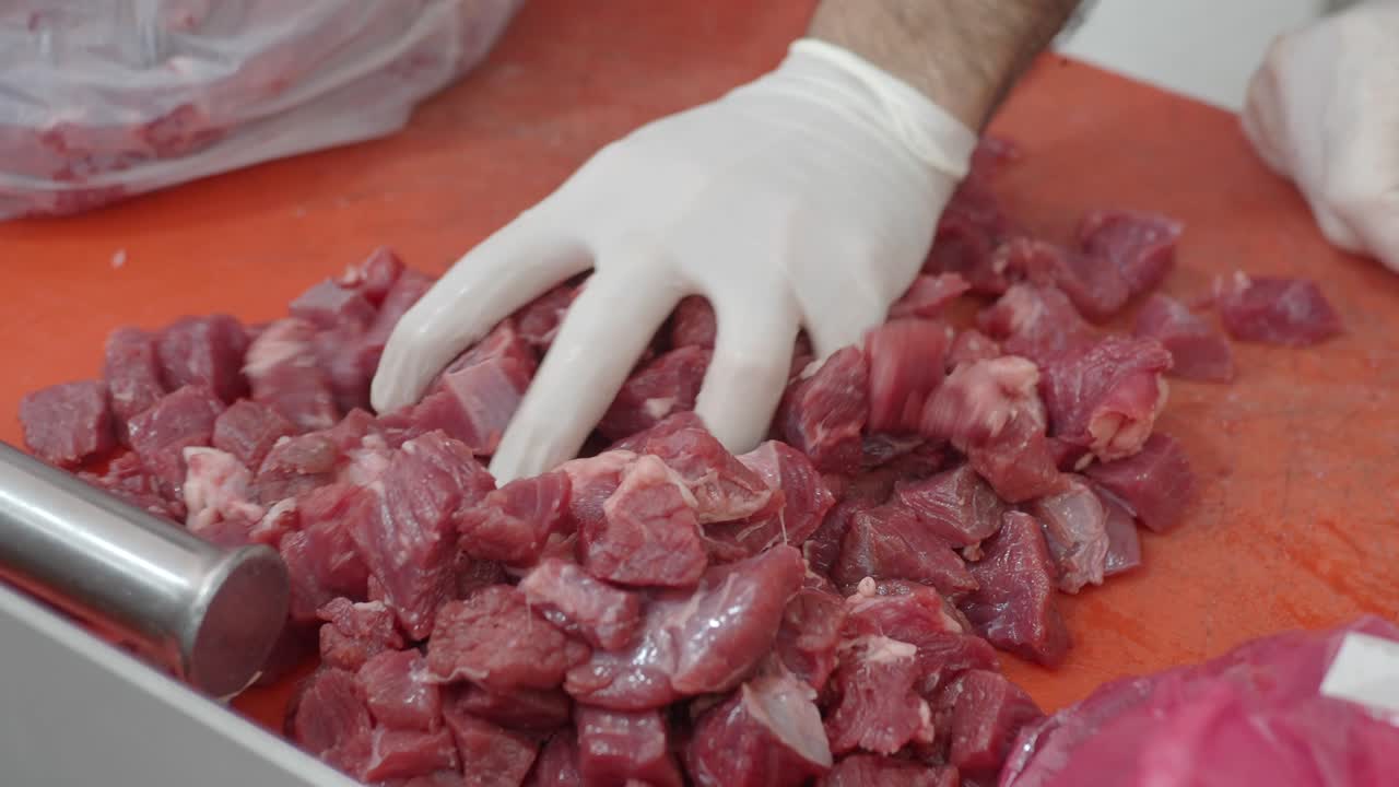 Diced Raw Meat on a Cutting Board with Gloved Hands