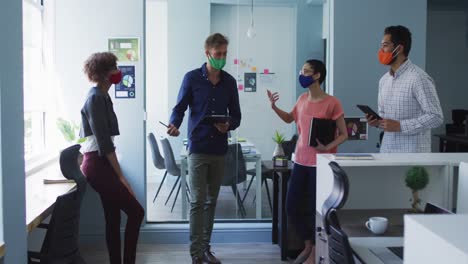 portrait of diverse colleagues wearing face masks discussing together at modern office