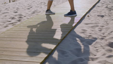 man and woman standing on wooden path on beach and exercising