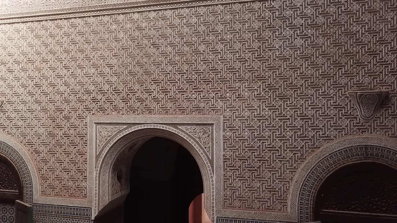 Primo piano di intricati motivi murali marocchini con intonaco intagliato e dettagli di piastrelle zellige. Ricche texture geometriche ideali per la grafica di design, architettura e patrimonio culturale.