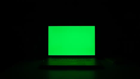 green screen laptop computer on a homework desk in dark room