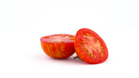 dos mitades de tomate a rayas de globo rojo. girando lentamente en la mesa giratoria aislado en el fondo blanco. primer plano. macro.