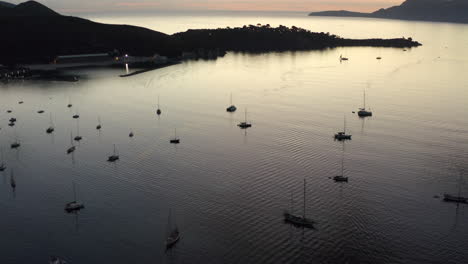 AERIAL:-Ocean-with-Sailboats-and-Tropical-Island-with-Mountains-in-Background-at-Sunrise-Vacation,-Travel,-Sunset