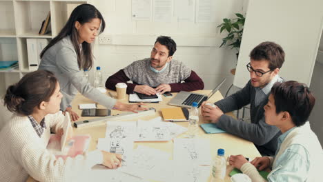 woman architect showing plans to hipster startup business team