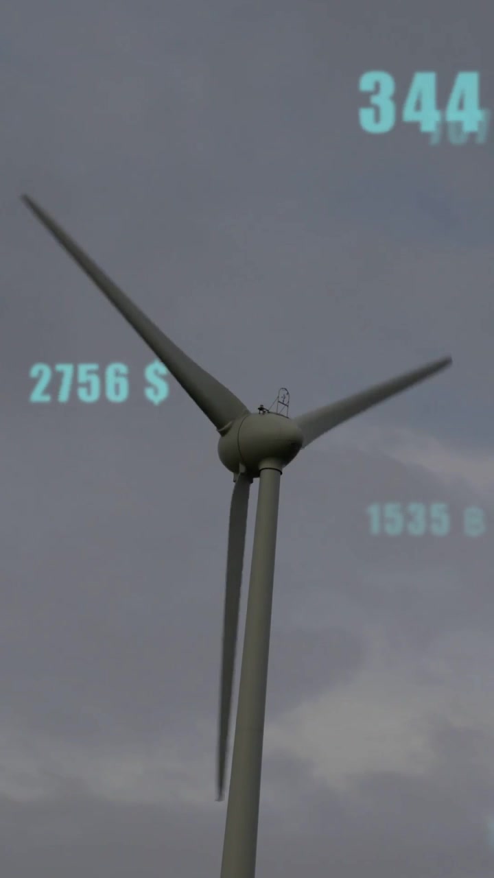 Vertical video: Wind turbine rotating as wind rising, showing finance numbers floating around rotor