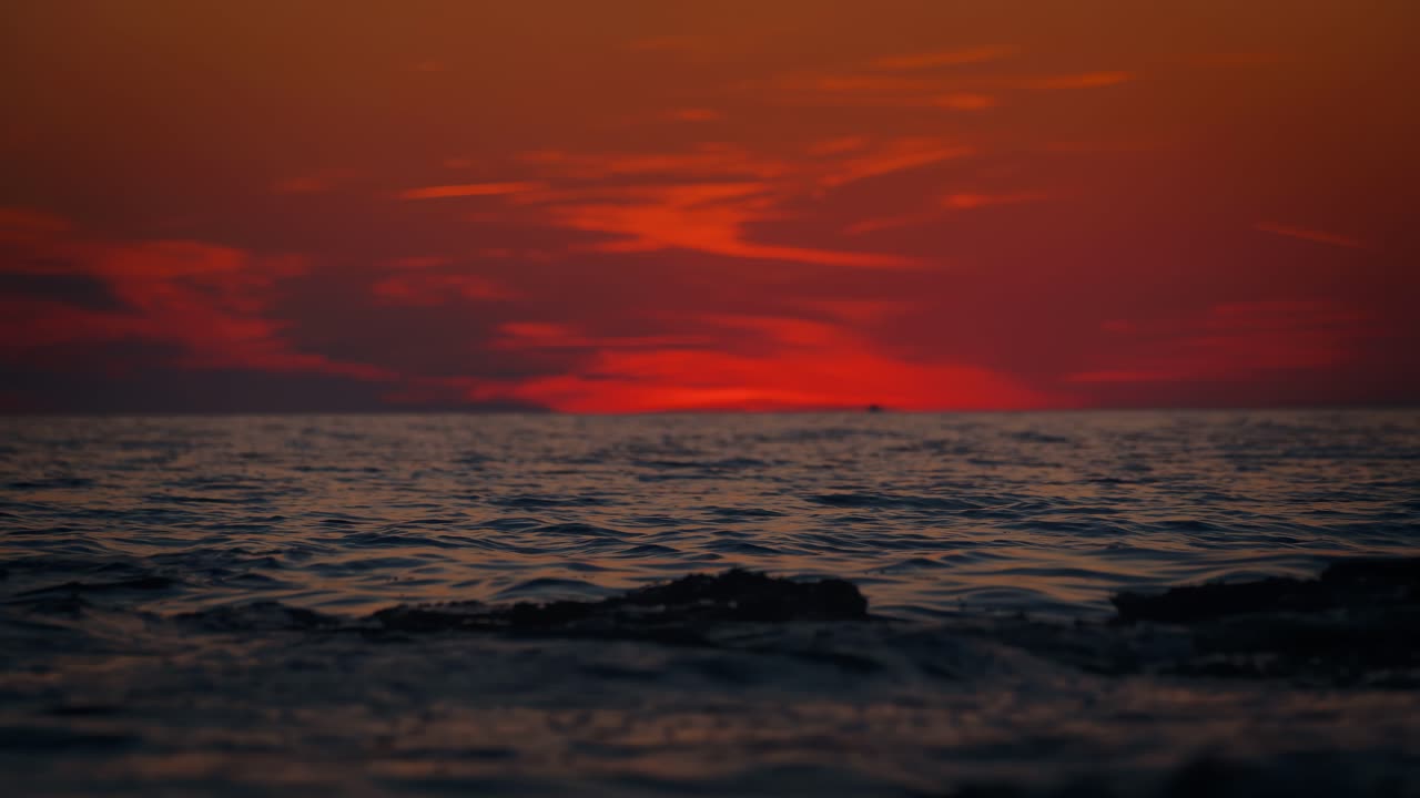 Dramatic red sunset clouds and sea reflections along the Istrian coast, Croatia. Wave close up