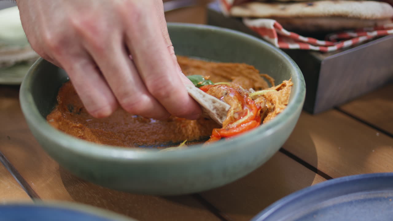 레스토랑 테이블 근접에서 피타와 함께 험무스를 먹는 남자. 음식을 즐기는 남자