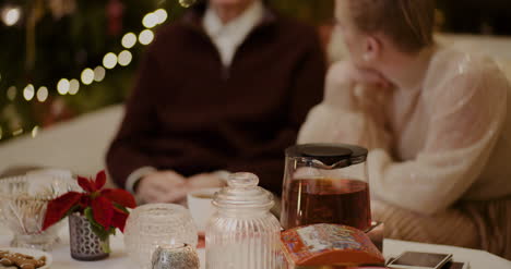 Mujer-Escuchando-Al-Abuelo-En-Casa-Durante-La-Navidad