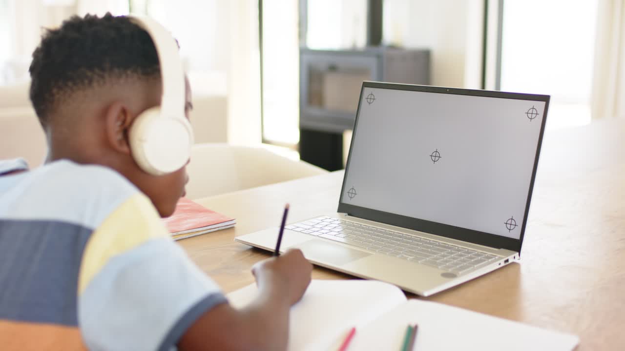 Ved lektionens start løfter eleven blyanten, skriver noter og kigger på den bærbare computer for at følge onlinelektionen