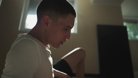 exhausted man athlete rubs wet hair with hand sitting on floor in club for fighting sports. rest after active movements. sweat dripping from forehead and feeling tired after workout