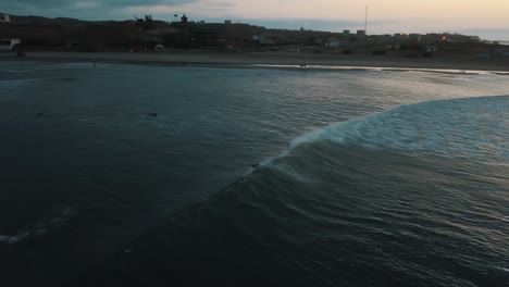 drone aerial of waves crashing hard on a surfer during sunset in peru