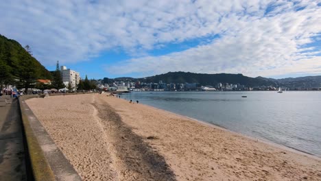 Malerische-Aussicht-Auf-Den-Weißen-Sandstrand-Von-Oriental-Bay,-Die-Uferpromenade-Und-Den-Hafen-An-Einem-Sonnigen-Tag-Mit-Blauem-Himmel-In-Der-Hauptstadt-Wellington,-Neuseeland-Aotearoa