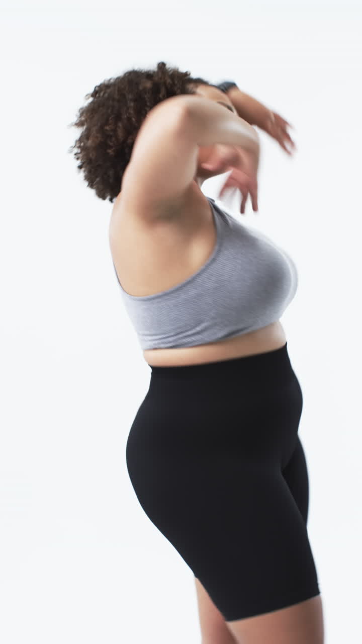Video verticale: Donna curvy che balla con gioia in abbigliamento sportivo, celebrando la positività corporea.