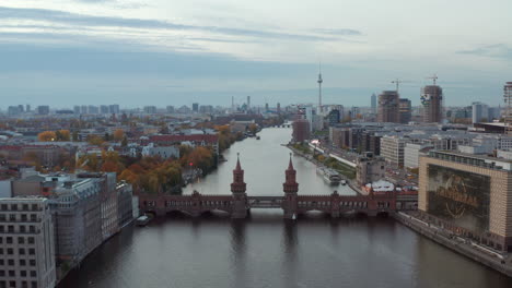 Berlín-Estableciendo-Una-Toma-Del-Horizonte-Urbano-Con-El-Río-Spree,-El-Puente-Oberbaum-Y-Los-Sitios-De-Construcción-Con-La-Torre-De-Televisión-Alexanderplatz-En-La-Distancia,-Vista-Aérea-Amplia