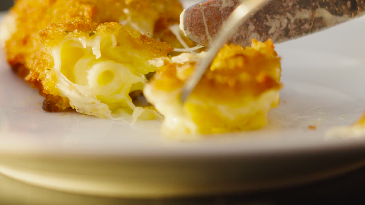 Delicious Crispy Mac and Cheese Pasta Croquette Being Cut into with Knife and Fork Cutlery in Slow Motion on White Plate. High Quality Tasty Food Footage