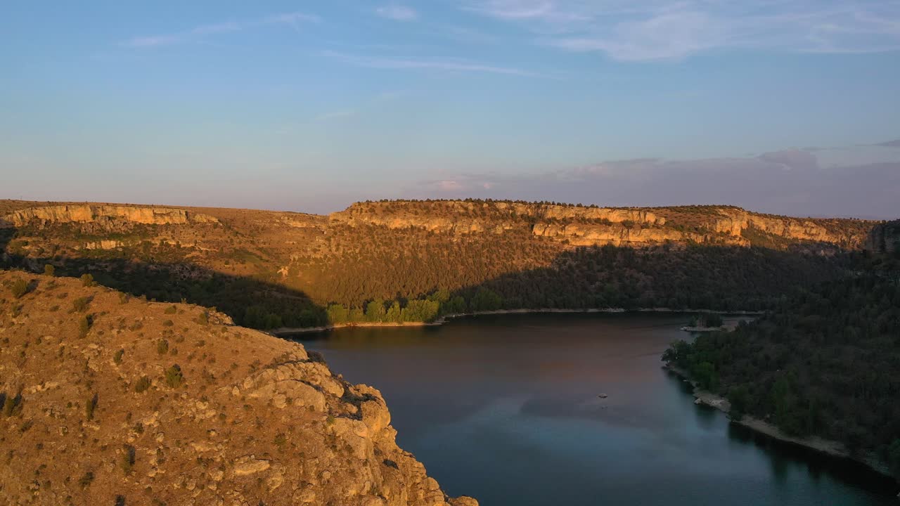 석회암 협곡에 위치한 저수지 위의 드론 비행 카메라를 좌우로 돌려 배경에는 나무가 있습니다. 여름에 푸른 하늘과 함께 해가 지는 황금 시간에 세고비아 스페인.