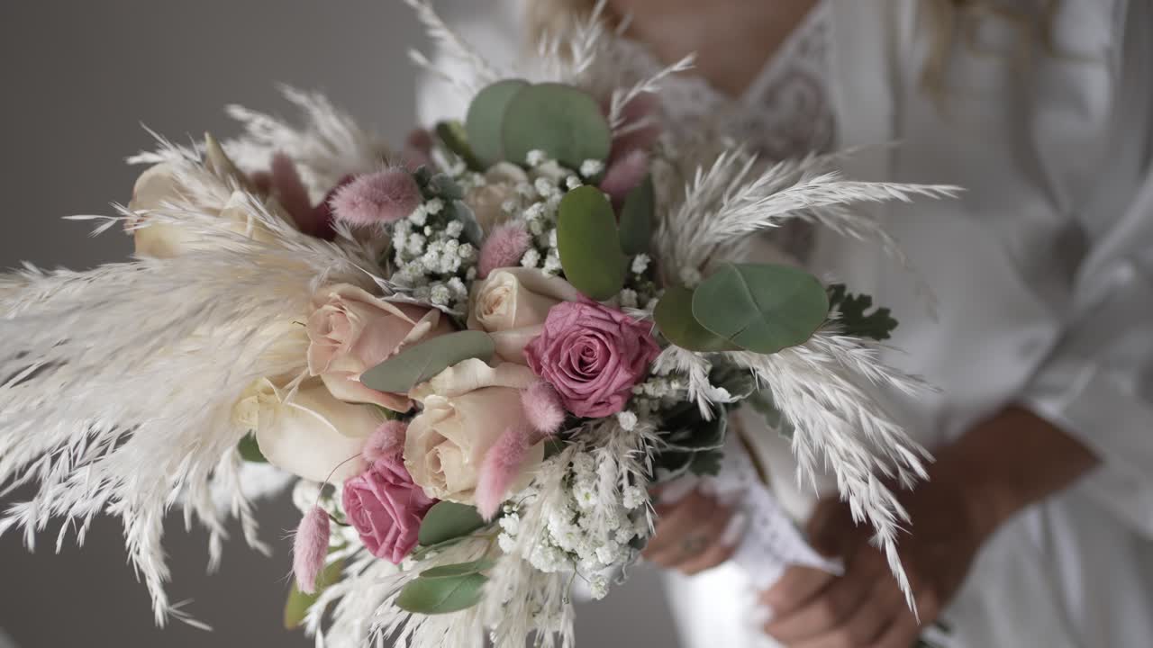 Bride holding a delicate bouquet of roses, eucalyptus, and pampas grass