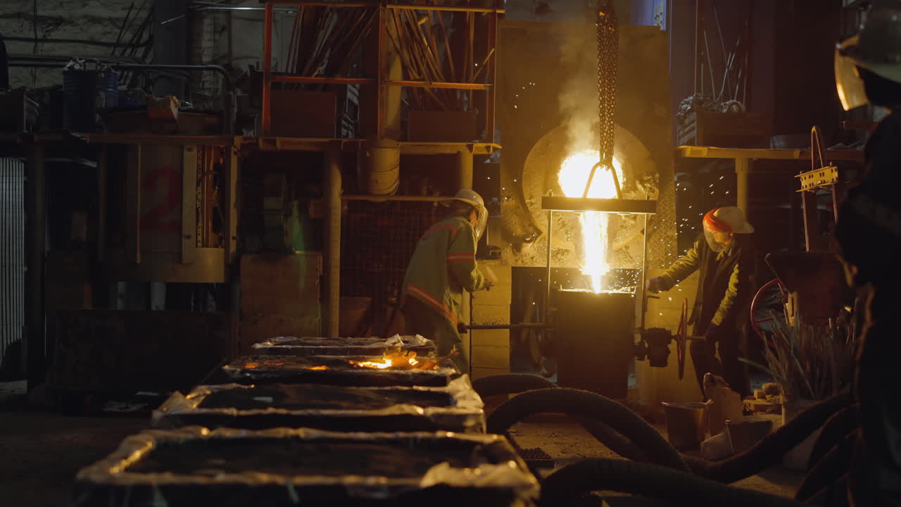 Industrial foundry workers pour molten metal with intense flames and smoke