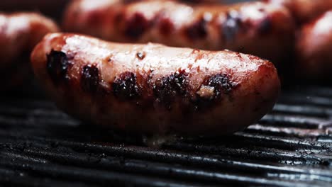 salchicha a la parrilla en una barbacoa mientras chisporrotea en una parrilla caliente en llamas
