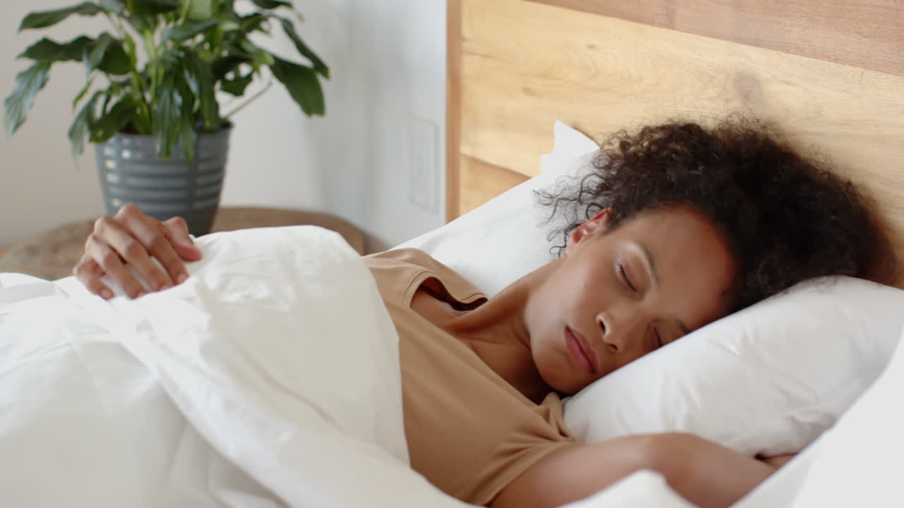 Woman peacefully sleeping in bed with white sheets, enjoying restful morning, at home