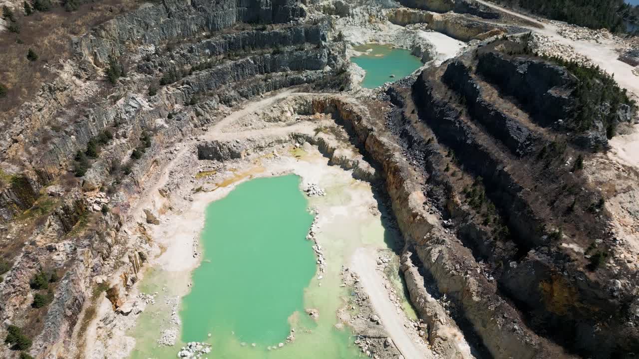 Drone shot of an open talc mine quarry in Manuels, Newfoundland Canada revealing the toxic aquamarine blue water within