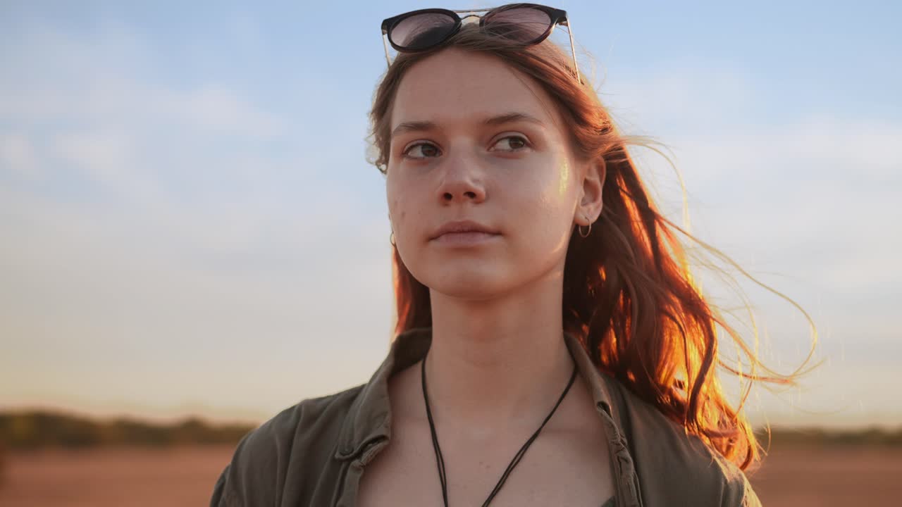 Young woman looking pleased into distance at golden hour, slow motion