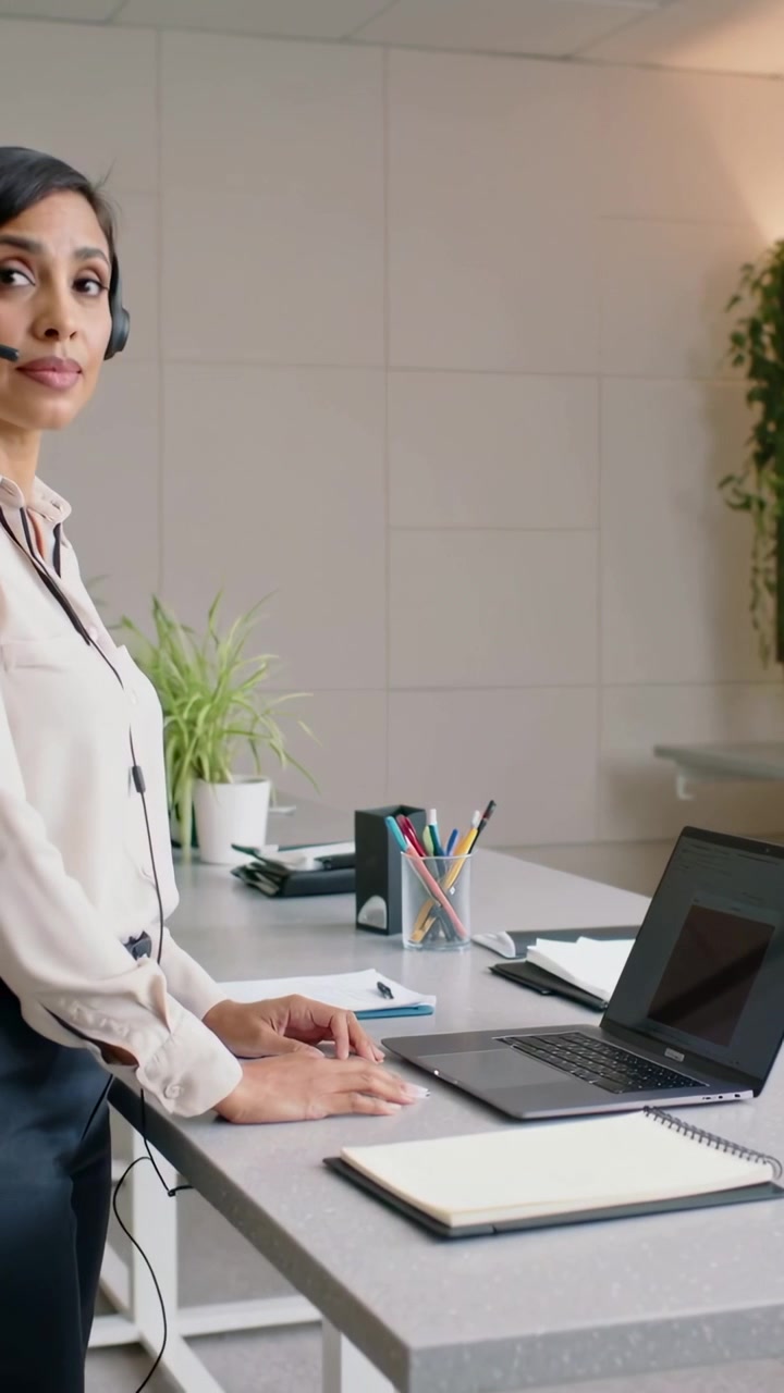 Video verticale: Telefono che squilla, donna in camicetta con microfono che sfoglia appunti, che digita al PC sulla scrivania, spazio per il testo